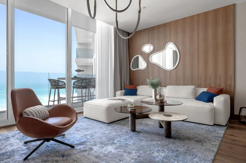 Living room with a leather swivel armchair and a view of the Saadiyat beach through full-height windows