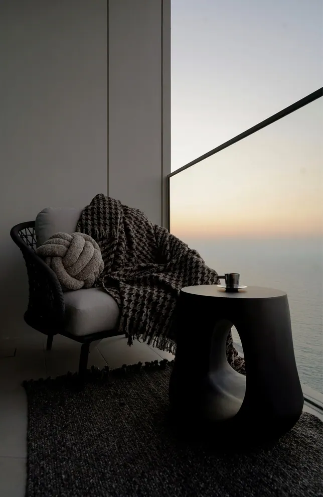 Balcony lounge chair with a houndstooth throw at sunset over the Arabian Gulf