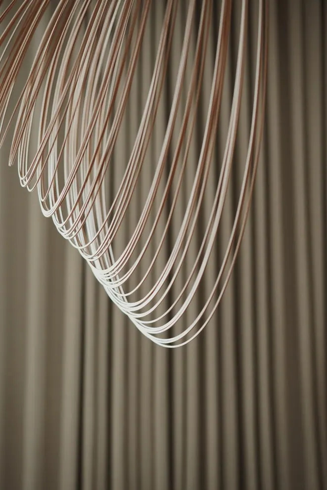 Detail of a pendant made of fine bent rods against linen curtains