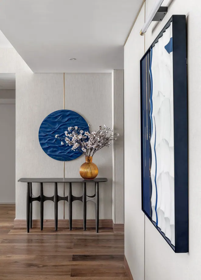 Hallway with a black sculptural console, a blue relief roundel and concealed storage with brass inlays