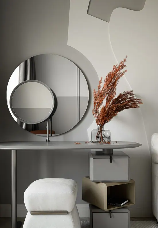 Custom vanity with a round mirror in a plaster arc, offset drawers and a boucle stool