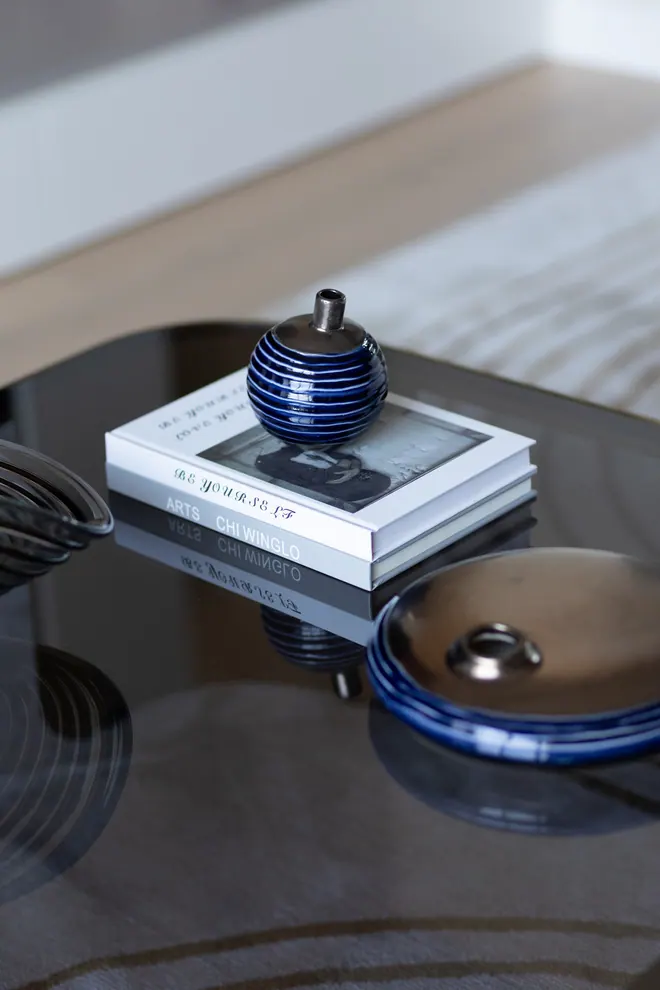 Smoked glass coffee table with art books and blue ceramic objects