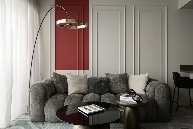 Rounded chenille sofa against grey wall mouldings with an arc floor lamp and a black glass table